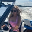 Joanna Opozda w różowym kostiumie kąpielowym za sterami motorówki