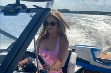 Joanna Opozda w różowym kostiumie kąpielowym za sterami motorówki