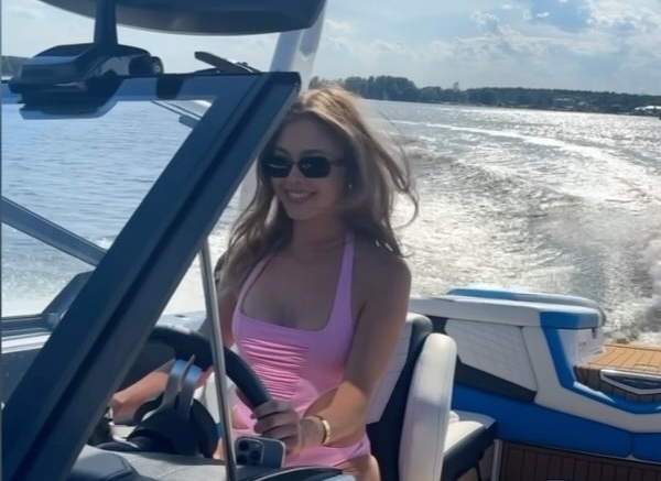 Joanna Opozda w różowym kostiumie kąpielowym za sterami motorówki